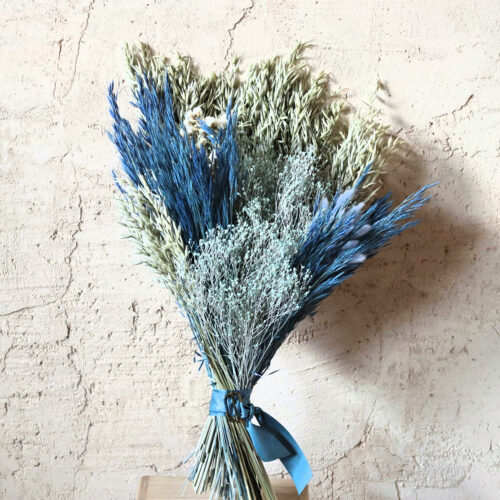 Ramo de flores secas Hilma en azules y verde salvia sobre pared encalada