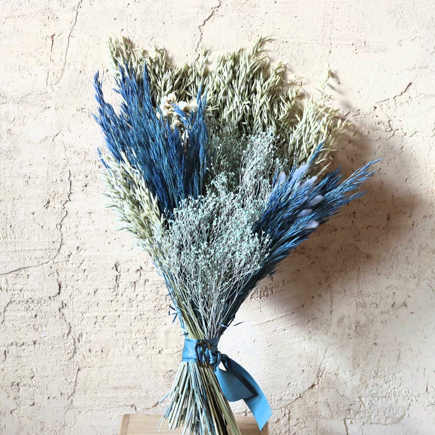 Ramo de flores secas Hilma en azules y verde salvia sobre pared encalada