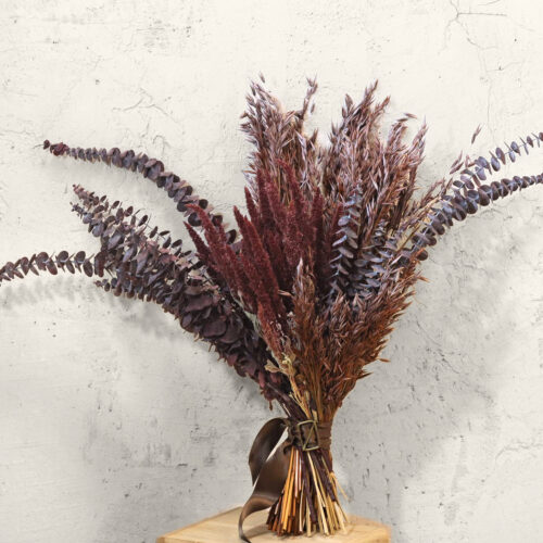 Ramo de flores secas Maroon en burdeos, castaño y ciruela sobre pared clara