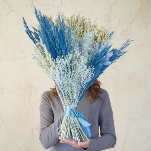 Ramo de flores secas Hilma en azules y verde salvia sobre pared encalada